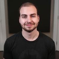 Man with short hair in a black shirt, smiling.