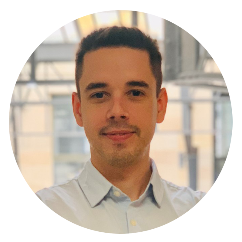 Man in a light blue shirt smiling indoors.