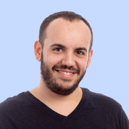 Smiling man in black shirt, light blue background.