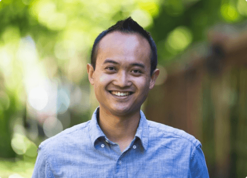 Man smiling outdoors with green background