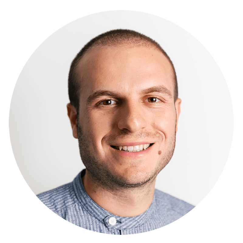 Smiling man with a shaved head and blue shirt.