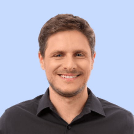 Smiling man in a black shirt on a blue background.