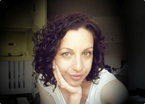 Woman with curly hair, resting chin on hand.